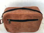 Brown leather toiletry bag with black zipper on a white background