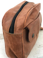 Brown leather bag with a black zipper on a light gray background