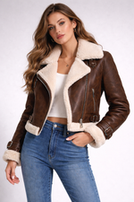 Woman wearing a brown leather jacket with white fur lining on a plain background