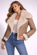 Woman wearing a beige shearling jacket with white fur trim on a white background