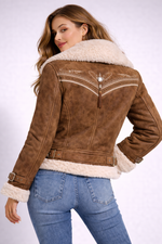 Woman wearing a brown suede jacket with white fur lining on a white background