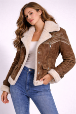 Woman wearing a brown shearling jacket with white fur lining on a white background
